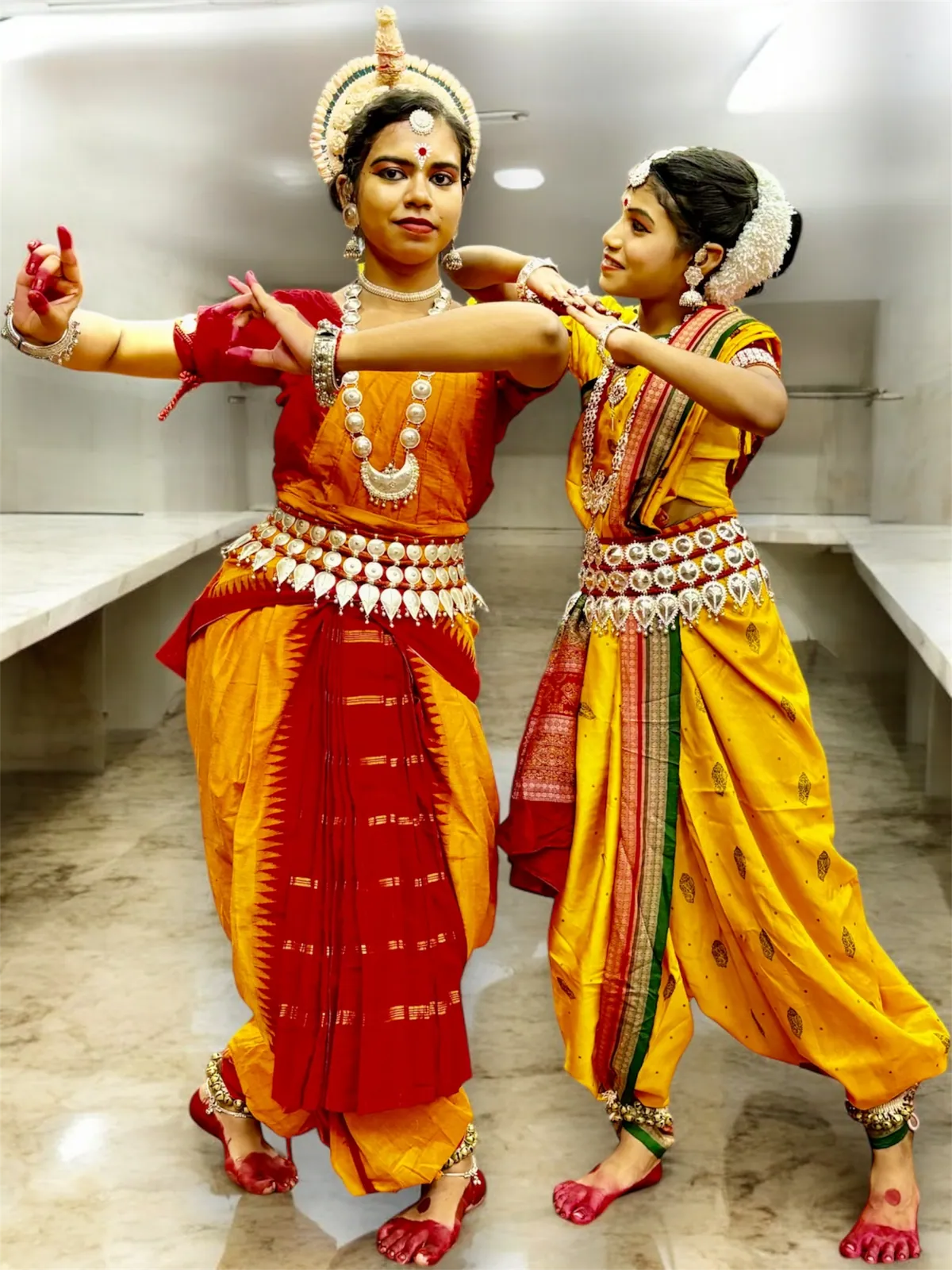 Two dancers in yellow and red costumes performing together indoors