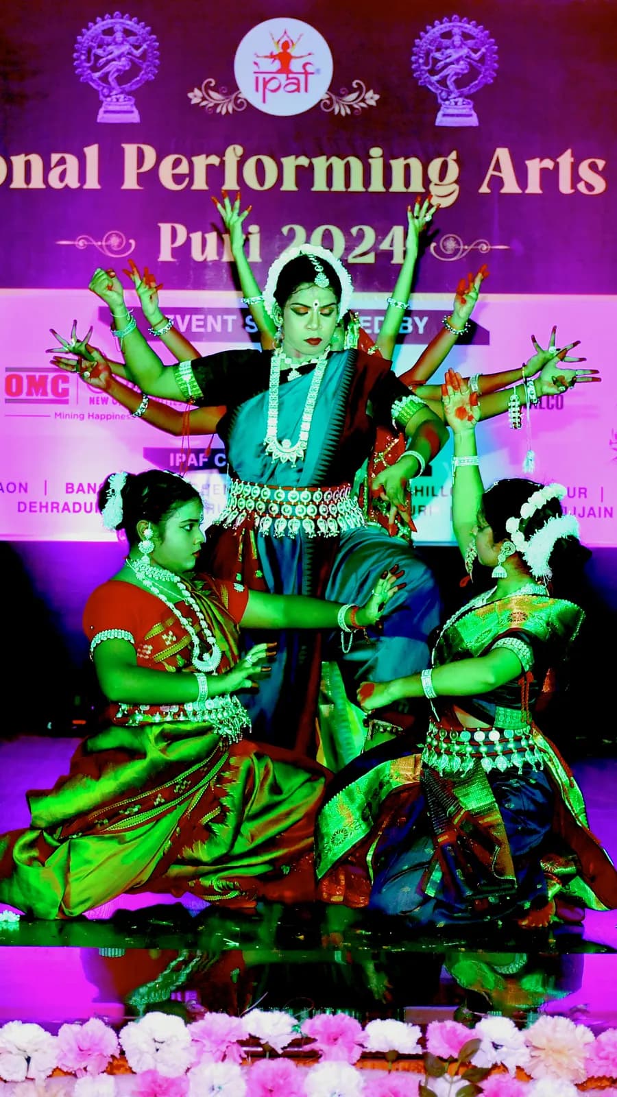 The troupe performing on a red-carpeted festival stage before a decorated backdrop
